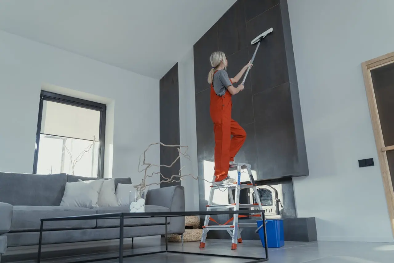 Cleaner on a ladder in a bright living room